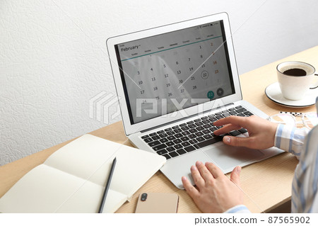 Woman using calendar app on laptop in office, closeup 87565902
