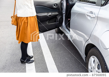 A woman getting in and out of a car in the parking lot 87568091