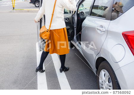 A woman getting in and out of a car in the parking lot 87568092