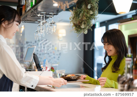 Young female customer receiving pasta at the counter of a self-service cafe 87569957