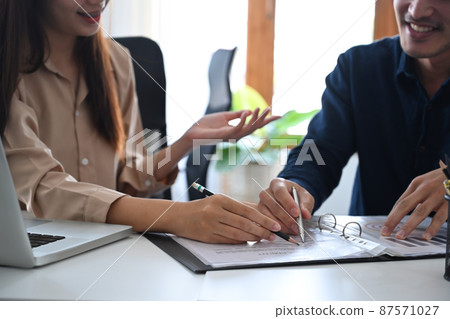Two young businesspeople having discussion about business report, financial graph at office desk. Two young businesspeople having discussion about business report, financial graph at office desk. 87571027