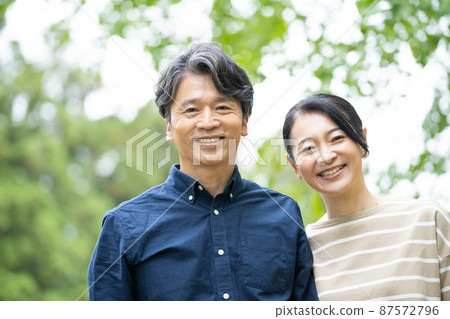 Middle-aged couple smiling with fresh green in the background 87572796