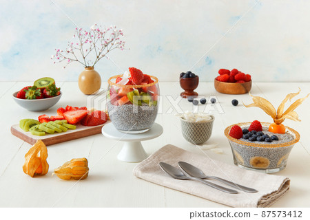Low angle view of chia pudding dessert with summer berries, strawberries, kiwi and coconut slices, embellished with a mint sprig. No people. 87573412