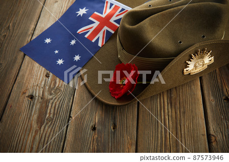 Anzac army slouch hat with Australian Flag and Poppy on wooden background 87573946
