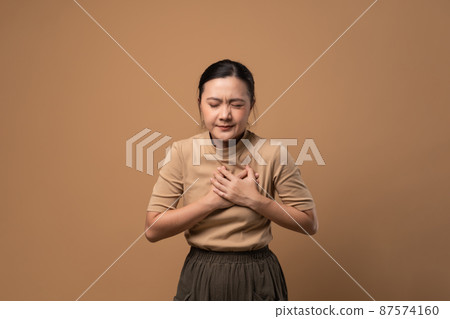 Asian woman was sick with chest pain isolated on beige background. Asian woman was sick with chest pain isolated on beige background. 87574160