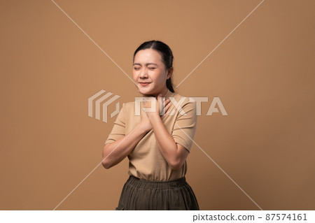 Asian woman was sick with sore throat standing isolated on beige background. Asian woman was sick with sore throat standing isolated on beige background. 87574161