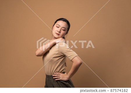 Asian woman was sick with body pain standing isolated on beige background. Asian woman was sick with body pain standing isolated on beige background. 87574182