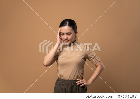 Asian woman was sick with headache standing isolated on beige background. Asian woman was sick with headache standing isolated on beige background. 87574198