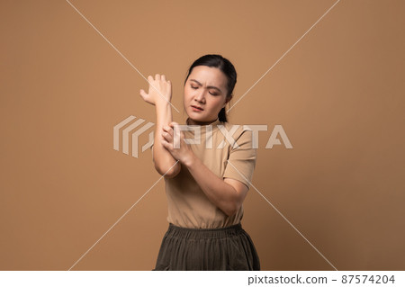 Asian woman was sick with irritate itching her skin standing isolated on beige background. Asian woman was sick with irritate itching her skin standing isolated on beige background. 87574204