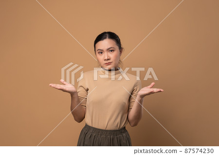 Asian woman feel confuse, standing isolated on beige background. Asian woman feel confuse, standing isolated on beige background. 87574230