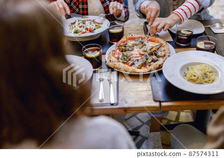 Friendly company enjoying delicious food in restaurant Friendly company enjoying delicious food in restaurant 87574311