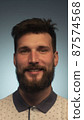 Portrait of smiling bearded young male model rejoices coming weekends, dressed casually, over blue background. Happy face smiling looking at the camera 87574568