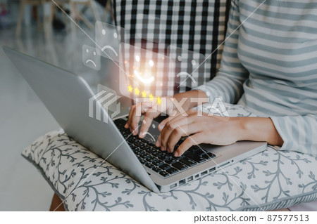 Customer service satisfaction survey concept, Business person using laptop computer and  pressing smiley face emoticon on virtual touch screen, Customer service evaluation concept. 87577513