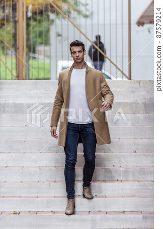 Handsome young man outdoor in winter fashion, wearing woolen jacket in city setting 87579214