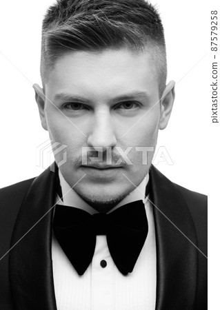 Confident attractive young man in black tuxedo Confident attractive young man in black tuxedo 87579258
