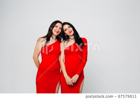 Two sexy sisters twins in red dresses. 87579811