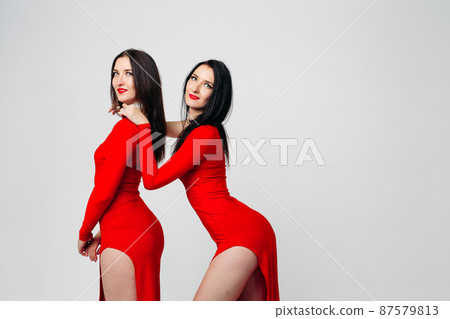 Two sexy sisters twins in red dresses. 87579813
