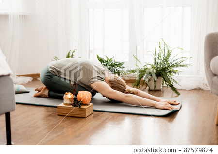 Beautiful young woman doing exercises and doing yoga at home 87579824