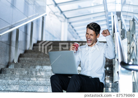happy man with a takeaway coffee looking at the screen of his laptop . happy man with a takeaway coffee looking at the screen of his laptop . 87579860