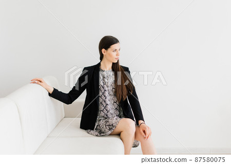 Cozy living room happy woman sitting on couch. European female enjoy lazy weekend or vacation 87580075