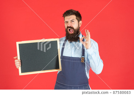 Happy winking man in barber apron hold school blackboard showing OK, enrollment 87580083