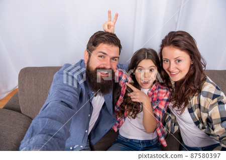 happy mother father and daughter making selfie sit on sofa together, family weekend happy mother father and daughter making selfie sit on sofa together, family weekend 87580397
