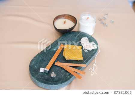 Close-up high-angle view of components for production of aromatic eco handmade candles on light background. Closeup composition with ingredients for scented home-made candles. Close-up high-angle view of components for production of aromatic eco handmade candles on light background. Closeup composition with ingredients for scented home-made candles. 87581065