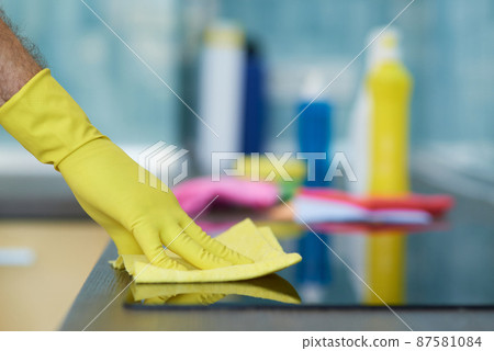 Quality cleaning. Close up shot of hand of man, professional male cleaner wearing gloves while cleaning oven in the kitchen 87581084