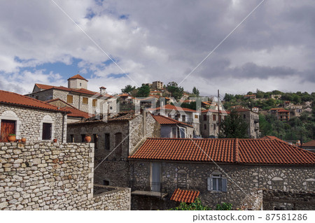 Greek village with traditional stone built houses against sky with clouds. Greek village with traditional stone built houses against sky with clouds. 87581286