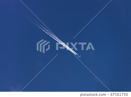 Route of an airplane with white contrail in the blue sky. 87581750