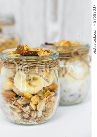 Healthy breakfast. Oatmeal Granola with greek yogurt and nuts banana muesli in jars on light background. Vegan, vegetarian and weight loss diet concept. Detox menu. Healthy breakfast. Oatmeal Granola with greek yogurt and nuts banana muesli in jars on light background. Vegan, vegetarian and weight loss diet concept. Detox menu. 87582037