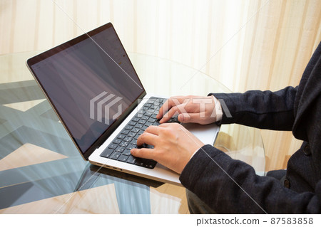 一位穿著西裝的辦公室工作人員，他鍵入筆記本電腦鍵盤來創建業務文檔 87583858