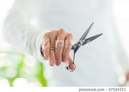 Hands of a beautician with scissors 87584351