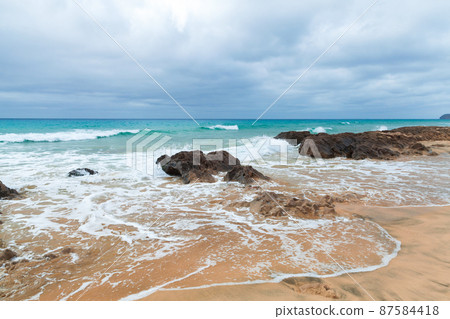 Coastal rocks and shore water on the beach 87584418