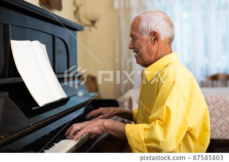 Elderly composer composes music and plays piano at home Elderly composer composes music and plays piano at home 87585803