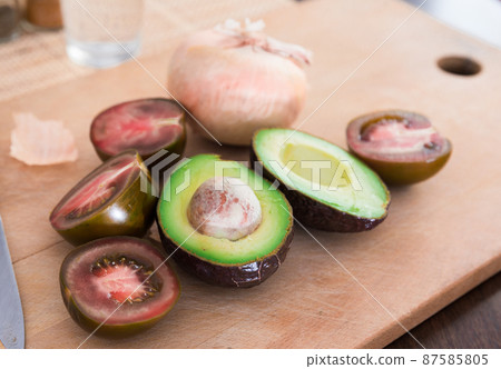 vegetables black tomatoes, avocado and onions on wooden board 87585805