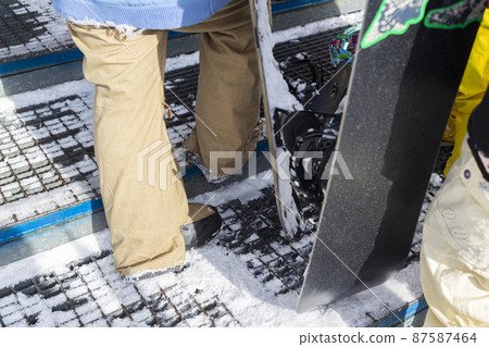 At the feet of people lining up in a gondola at a ski resort 87587464