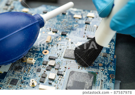Technician use brush and air blower ball to clean dust in circuit board computer. Repair upgrade and maintenance technology. Technician use brush and air blower ball to clean dust in circuit board computer. Repair upgrade and maintenance technology. 87587978