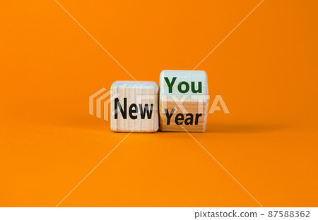 New year time. Turned a cube and changed the words 'new year' to 'new you'. Beautiful orange background. Copy space. Business and new year concept. New year time. Turned a cube and changed the words 'new year' to 'new you'. Beautiful orange background. Copy space. Business and new year concept. 87588362