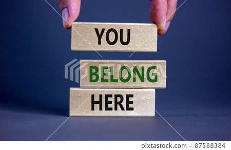 You belong here symbol. Wooden blocks with words 'You belong here' on beautiful grey background. Male hand. Diversity, business, inclusion and belonging concept. You belong here symbol. Wooden blocks with words 'You belong here' on beautiful grey background. Male hand. Diversity, business, inclusion and belonging concept. 87588384