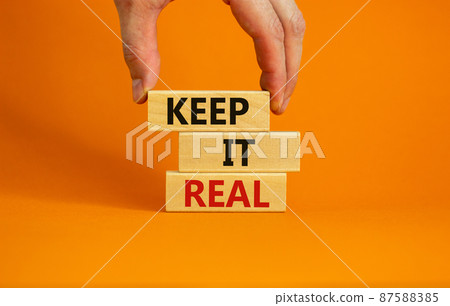 Male hand placing a blocks with word 'keep' on top of a blocks tower with words 'keep it real'. Beautiful orange background. Copy space. Business concept. 87588385