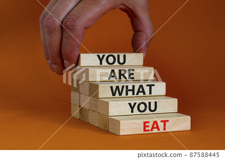 You are what you eat symbol. Wooden blocks with words 'You are what you eat'. Beautiful orange background, copy space. Doctor hand. Healthy eating concept. Copy space. You are what you eat symbol. Wooden blocks with words 'You are what you eat'. Beautiful orange background, copy space. Doctor hand. Healthy eating concept. Copy space. 87588445