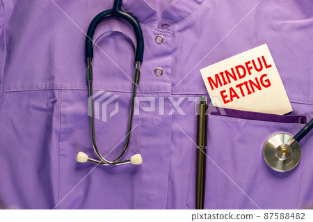 Mindful eating symbol. Medical uniform, white card with words Mindful eating, metalic pen and stethoscope. Medical and mindful eating concept. 87588482