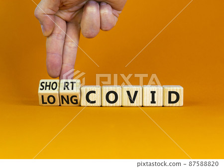 Long covid symbol. Doctor turnes wooden cubes and changes words 'short covid' to 'long covid'. Beautiful orange background, copy space. Medical, covid-19 pandemic long covid concept. 87588820