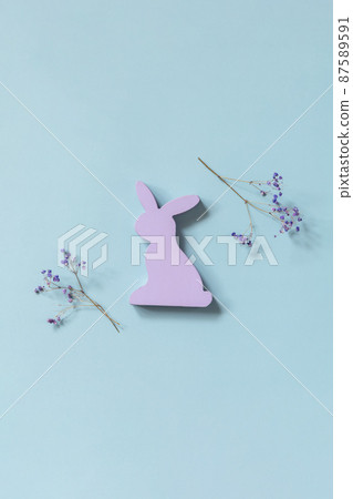 Happy Easter concept with purple rabbit, gypsophila flowers on a blue background. Easter background. Happy Easter concept with purple rabbit, gypsophila flowers on a blue background. Easter background. 87589591