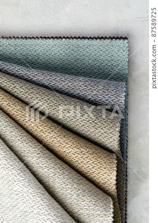 Fabric swatches in different colors are stacked for selection. A variety of shades of upholstery material for furniture and interior. Fabric texture close up. A set of multi-colored rolls of material Fabric swatches in different colors are stacked for selection. A variety of shades of upholstery material for furniture and interior. Fabric texture close up. A set of multi-colored rolls of material 87589725