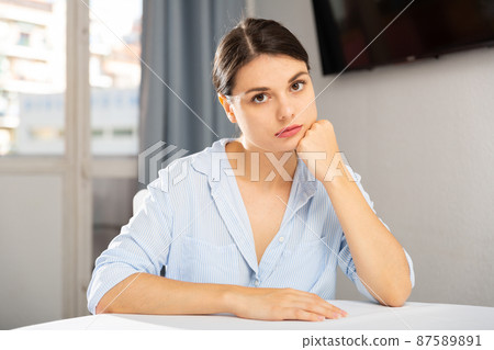 Portrait of sad girl sitting in living room at home 87589891