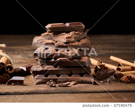 broken pieces of dark chocolate, cinnamon sticks and star anise on a brown wooden table 87590479