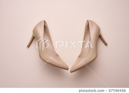 leather beige high heel shoes on a beige background, top view leather beige high heel shoes on a beige background, top view 87590486