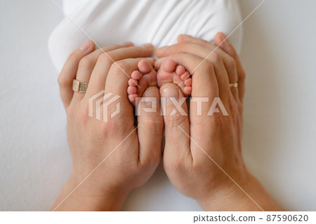 Small beautiful legs of a newborn baby in the first days of life Small beautiful legs of a newborn baby in the first days of life 87590620